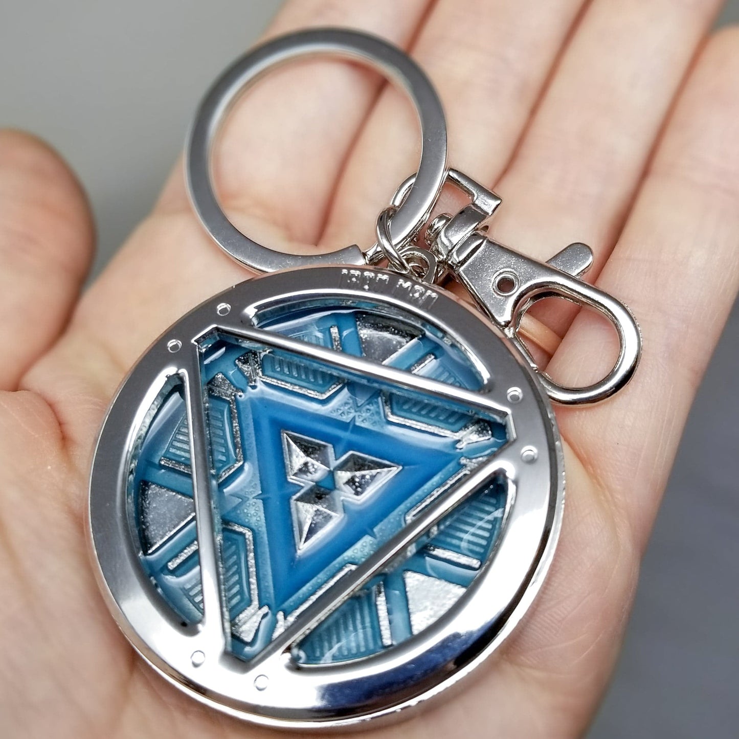 Iron Man Glow-In-The-Dark Pewter Arc Reactor Keychain. In Celebration of Tony Stark’s Iron Man as seen in the Marvel Studios Avengers films, this oversize pewter Arc Reactor glow-in-the-dark metal keychain features the Arc Reactor powering Tony’s chest and power suit in Iron Man 3. 2 inches across & nearly 1/2 inch thick! Features “Iron Man” logo on the back Includes stainless steel keyring and clip Blue Glow-in-the-Dark effect! Carry your own Proof that Tony Stark Has a Heart