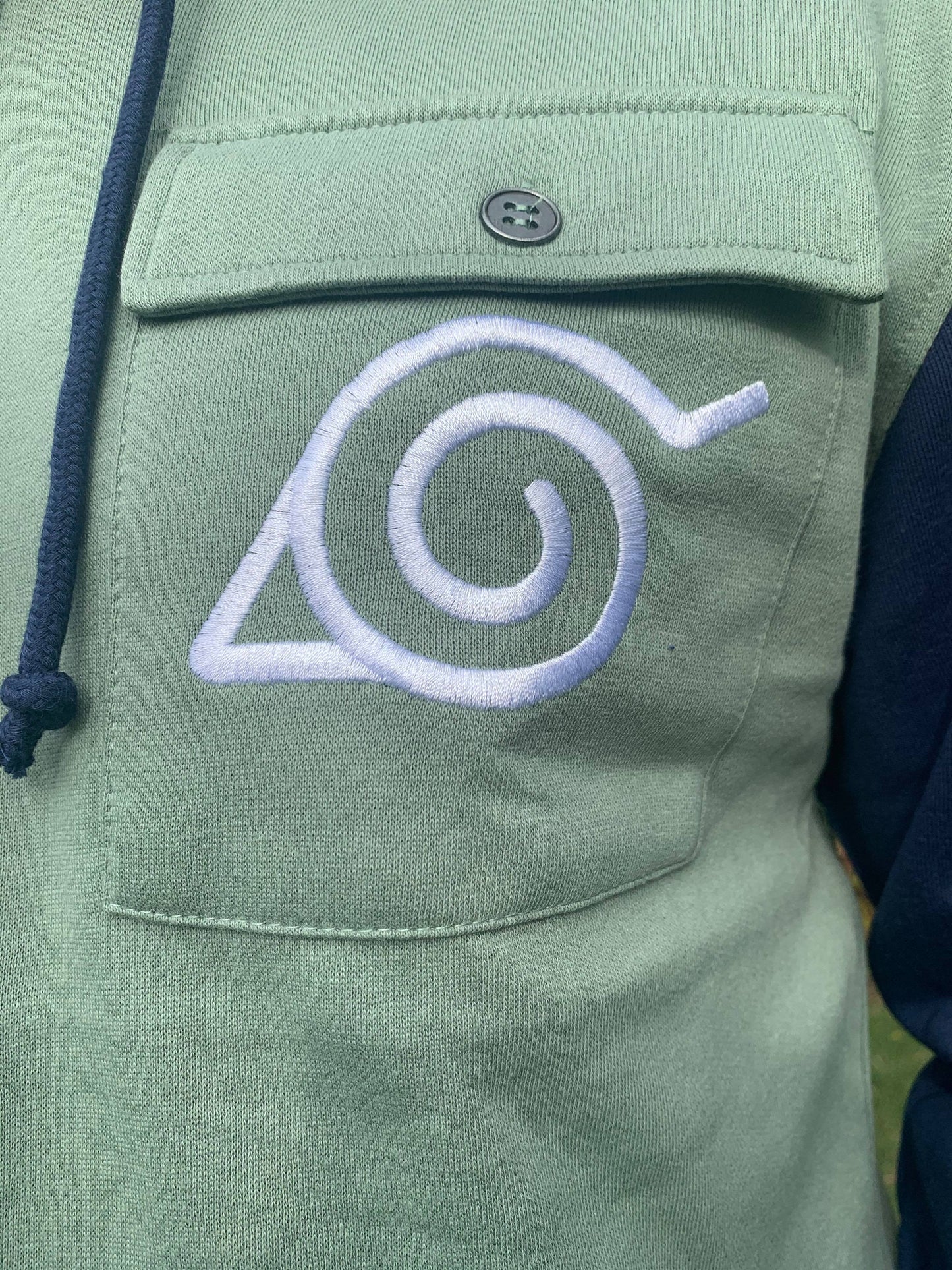 Officially Licensed Naruto Shippuden Military Style Kakashi Hoodie — a cozy zipper sweatshirt with incredible detail work including the Leaf Village emblem and the red swirl Uzumaki Clan Symbol. Officially Licensed 60/40% Cotton Polyester Machine washable