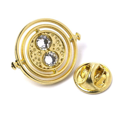 Fixed Time Turner Pin Badge  Worn by Hermione Granger, the Time Turner played a huge part in the Prisoner of Azkaban.  Please be aware that this fixed-pin design does not rotate. This Harry Potter Pin Badge has been created using the official style guide from Warner Bros.  Pin Details:  Around .75" tall and .5" wide (20mm x 16mm) Beautiful gold tone fixed-pin Time Turner with faux crystal bead detail Pin arrives on a printed Harry Potter card backer Quality metal badge pin with butterfly clutch backing  